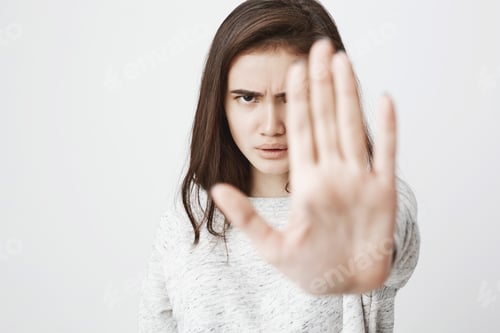 Preview: Studio shot of attractive european woman with concerned expression and frowned eyebrows, stretching