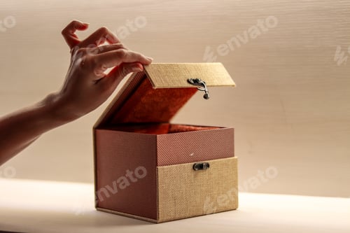 Preview: Female hand opening a box for accessories isolated on a wooden background