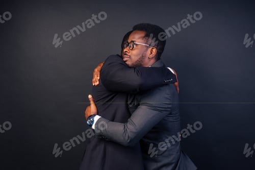 Preview: two business partners hugging in the studio on a black background
