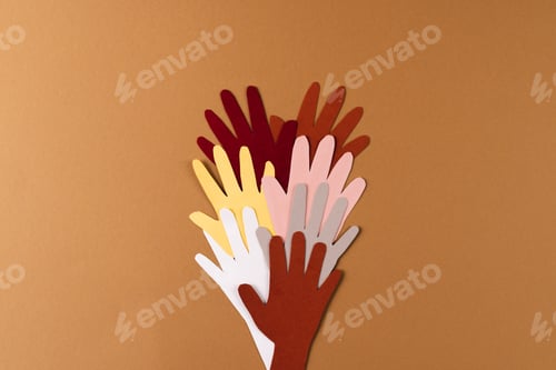 Preview: Paper cut out of multi coloured hands with copy space on brown background