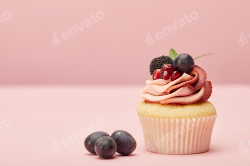 Preview: sweet cupcake with cream and grapes on pink surface