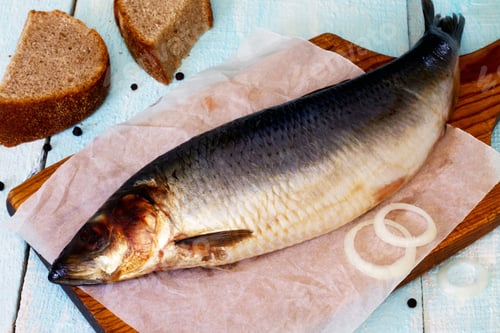 Preview: Salted herring on the paper, onion and bread on wooden background.