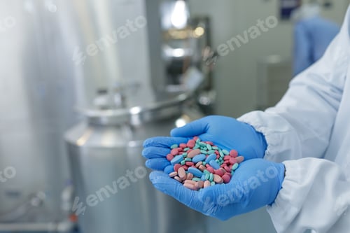 Preview: Pharmaceutical Worker Holds Colorful Pills in Sterile Manufacturing Facility