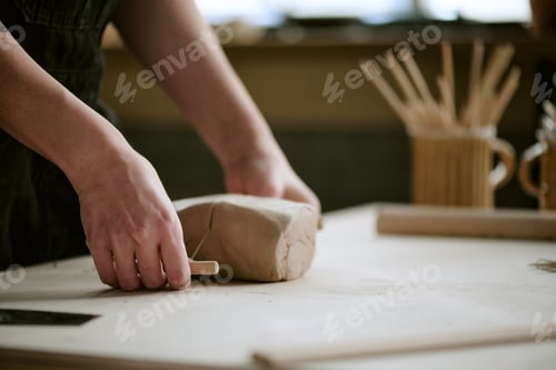 Preview: Woman Shaping Clay with Wooden Tool in Pottery Studio