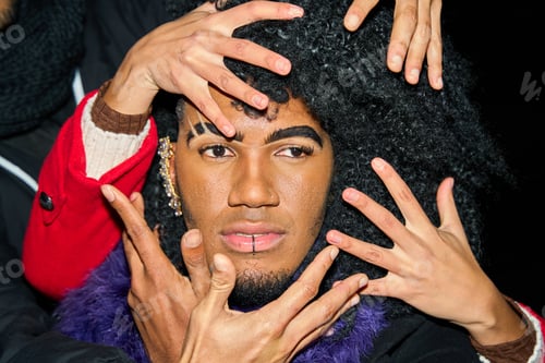 Preview: Many hands touching face of young drag queen performer