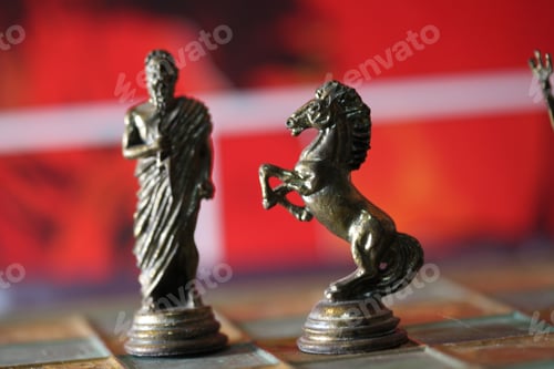 Preview: Closeup of Greek mythology chess pieces on the board with a red blurry background