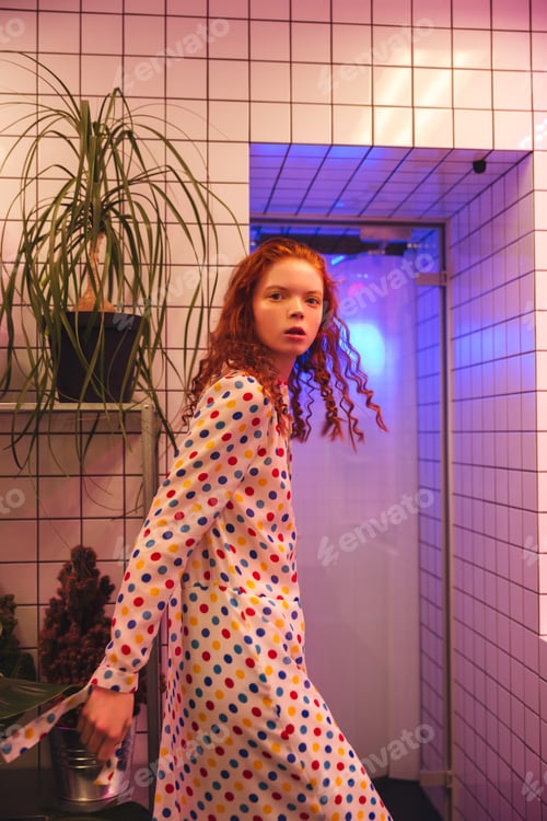Preview: Serious young redhead curly lady standing in cafe near latrine