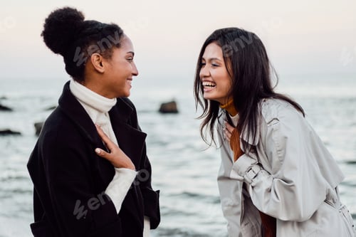Preview: Two cheerful casual girls happily talking walking together by the sea