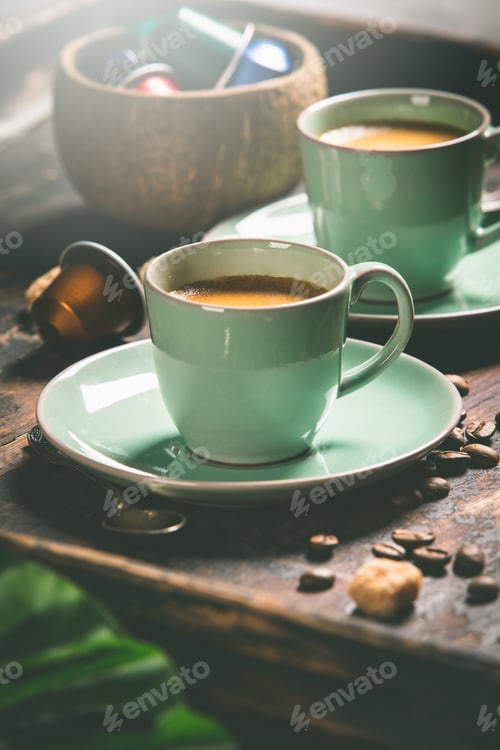 Preview: Cups of coffee and capsules, close up