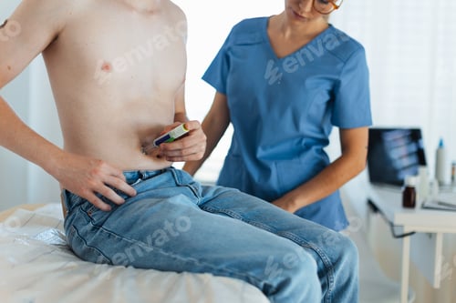 Preview: Diabetologist doctor teaching a teenage patient how to inject insulin into his abdomen, using