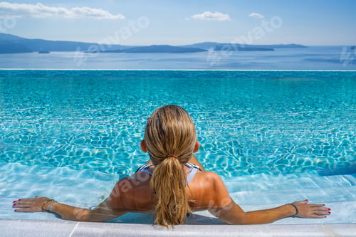 Preview: Woman at the swimming pool on the island of Santorini in Greece with view on the calde