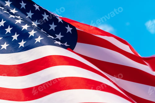 Preview: American flag waving in the wind against blue sky
