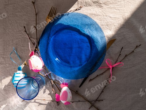 Preview: Happy Easter table setting blue glass plate fork knife tree branches on linen cloth. Festive menu