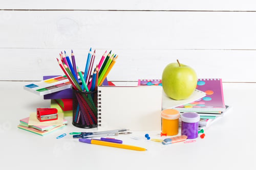 Preview: Colorful art supplies and fresh apple on a creative workspace during daytime