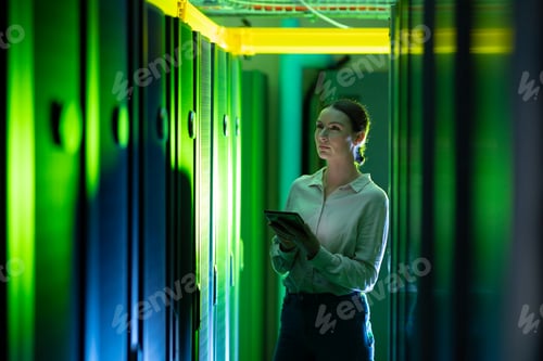 Preview: Caucasian female engineer using digital tablet while inspecting in computer server room