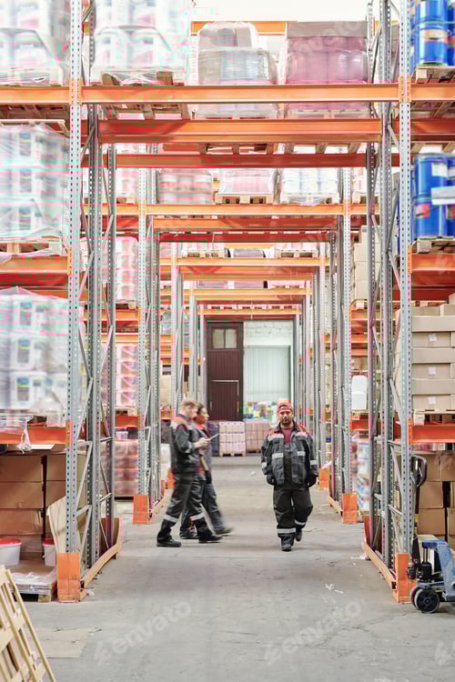Preview: Young mixed-race male warehouse worker in uniform moving along aisle