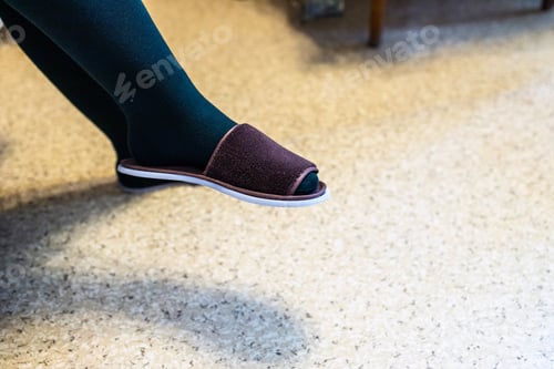 Preview: leg in dark tights and house slipper in apartment