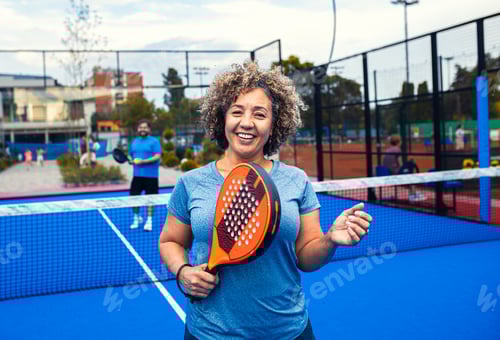 Preview: Portrait of woman playing padel with her friend on outdoor court.