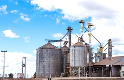 Preview: Rural area with grain storage silos and blue sky with clouds.