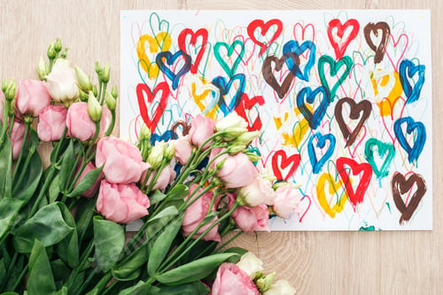 Preview: top view of bouquet with eustoma flowers and drawing with colorful hearts on wooden table