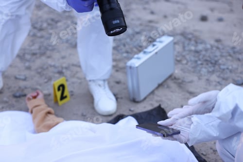 Preview: Forensic experts working at crime scene with dead body outdoors, closeup