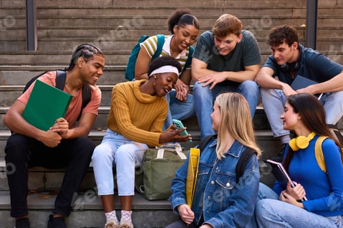 Preview: Diverse student group interacting, sharing smartphone on stairs