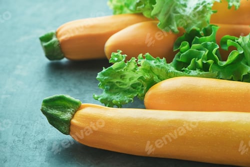 Preview: Four yellow zucchini and lettuce on kitchen table. Whole raw courgettes