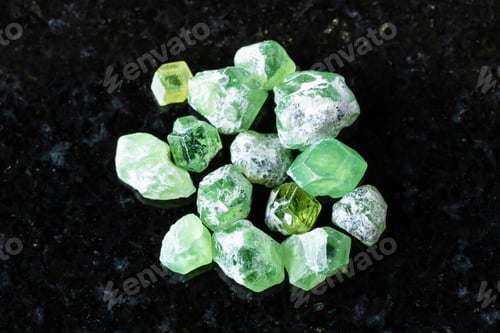 Preview: many raw demantoid crystals on black granite
