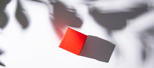 Preview: red gift box on white table with morning shadow. Top view and copy space.
