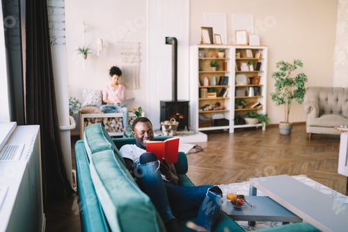 Preview: Man Reading on Couch While Woman Uses Laptop