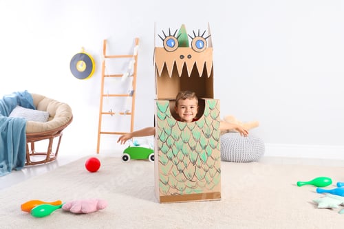 Preview: Cute little boy playing with cardboard dragon at home