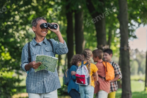 Preview: selective focus of happy african american kid looking through binoculars near friends