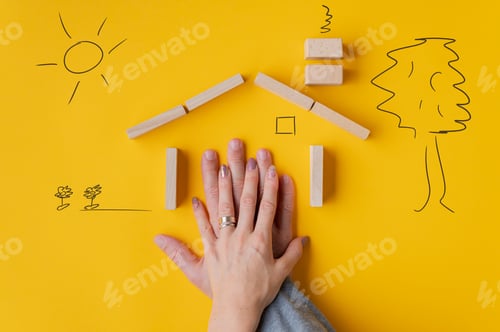 Preview: Hands of a couple in house made of wooden blocks