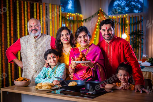 Preview: Indian family in traditional wear cooking food for diwali festival celebration at home - group photo