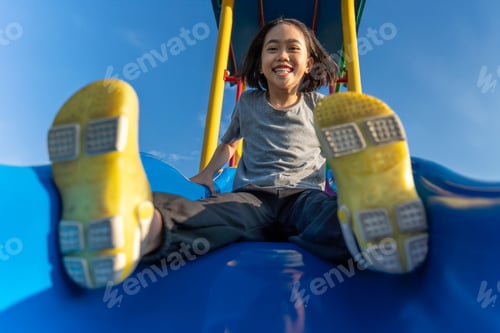 Preview: A little Asian girl playing at playground slide.