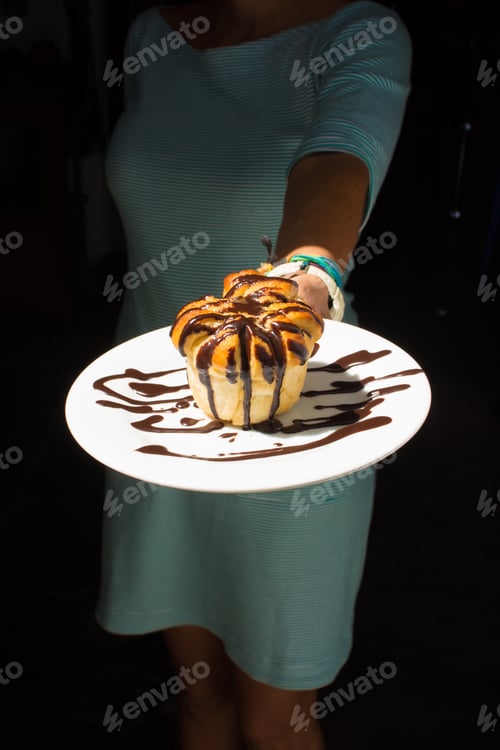 Preview: Chocolate dipped sweet bread on a white plate, held by a woman.