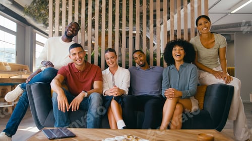 Preview: Portrait Of Multi-Cultural Business Team Sitting On Couch In Modern Open Plan Office Together