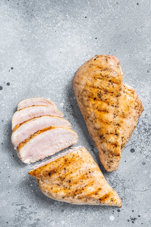 Preview: BBQ grilled and sliced chicken breast fillet steak. Gray background. Top view