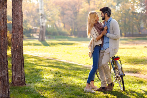 Preview: Couple with bicycle standing in park on sunny day.