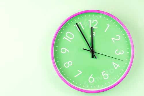 Preview: Closeup of colorful wall clock on green background.