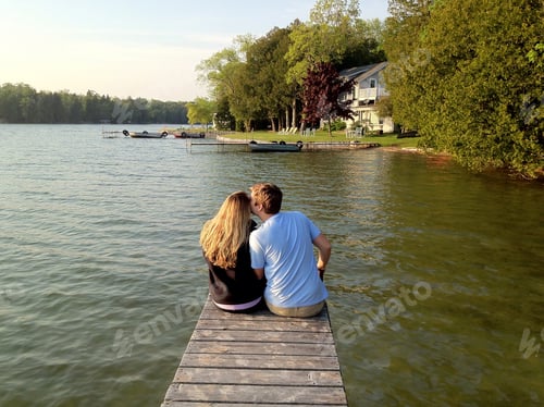 Preview: Cute young couple sitting on the end of a pier