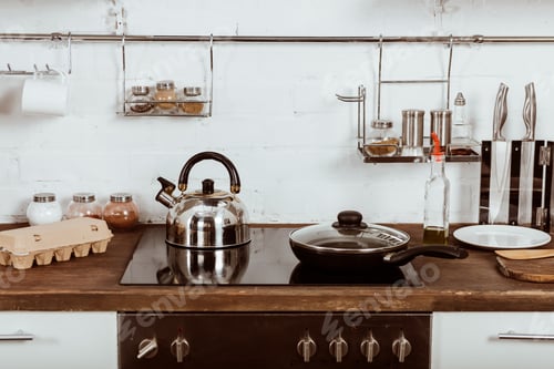 Preview: selective focus of modern kitchen interior with frying pan and teapot on stove