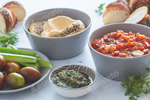 Preview: Vegetarian appetizers: hummus, roasted peppers salad, pesto and fresh vegetables.