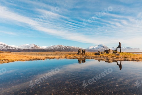 Preview: Man explorer in Iceland with his reflection on the water
