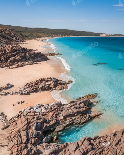 Preview: View of a pristine beach with turquoise waters and rocky formations on a sunny day.