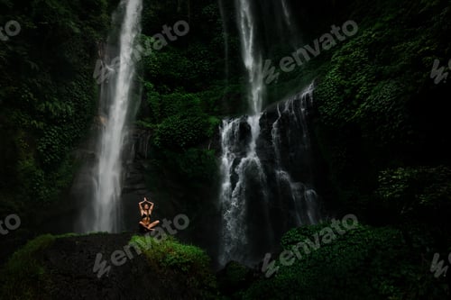 Preview: Beautiful young woman meditating in lotus position while doing yoga in a wonderful forest near