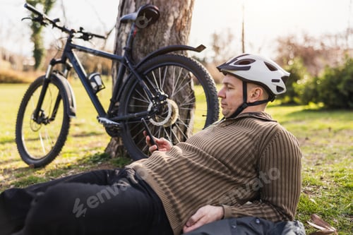 Preview: Man Checking Smartphone While Resting on a Meadow in a City Park