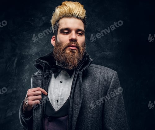 Preview: A stylish bearded man dressed in an elegant suit and coat standing against a dark textured wall
