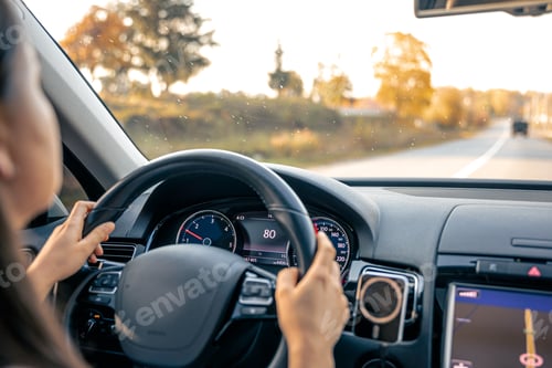 Preview: Woman driver hands on steering wheel inside car.