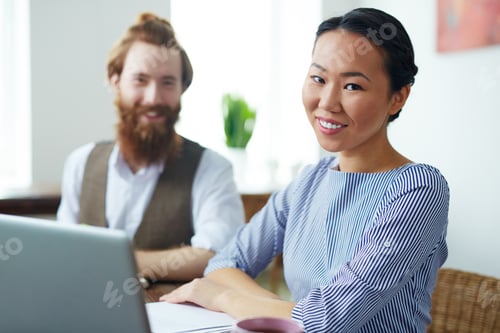 Smiling Woman with Coworker at Desk with Laptop